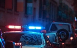 A police car with flashing red and blue emergency lights is parked on a city street, highlighting the urgency of law enforcement response. This image represents the critical role of video-verified alarms in reducing false alarms and ensuring faster police dispatch for businesses and commercial properties.